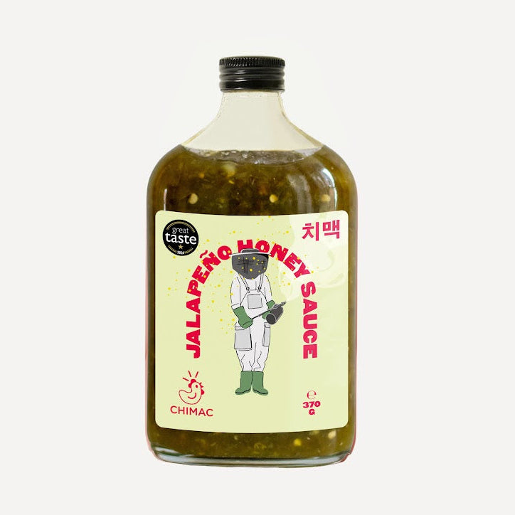 A bottle of Chimac Jalapeño Honey Sauce with a black cap and a cream-colored label featuring a beekeeper illustration and red text of the name, set against a plain light gray background.